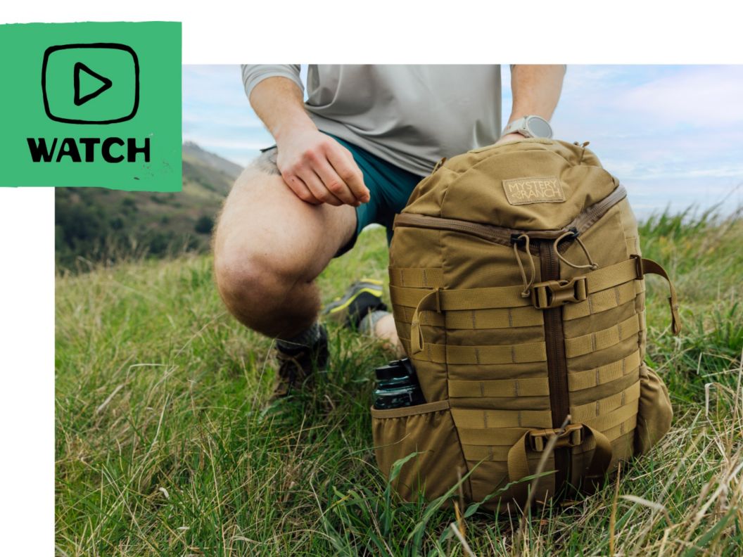 A man kneels in a grassy meadow with a tan daypack. Text reads:    How To Choose A Hiking Daypack    Pick Your Fit, Features & Capacity        